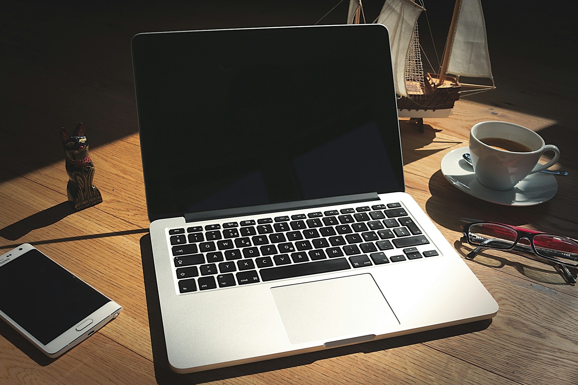 Laptop and smartphone on a wooden desk in soft, low light
